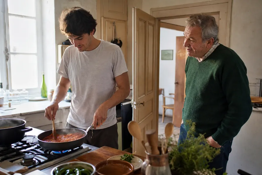 Un chef à domicile prépare un repas dans une cuisine de voisin